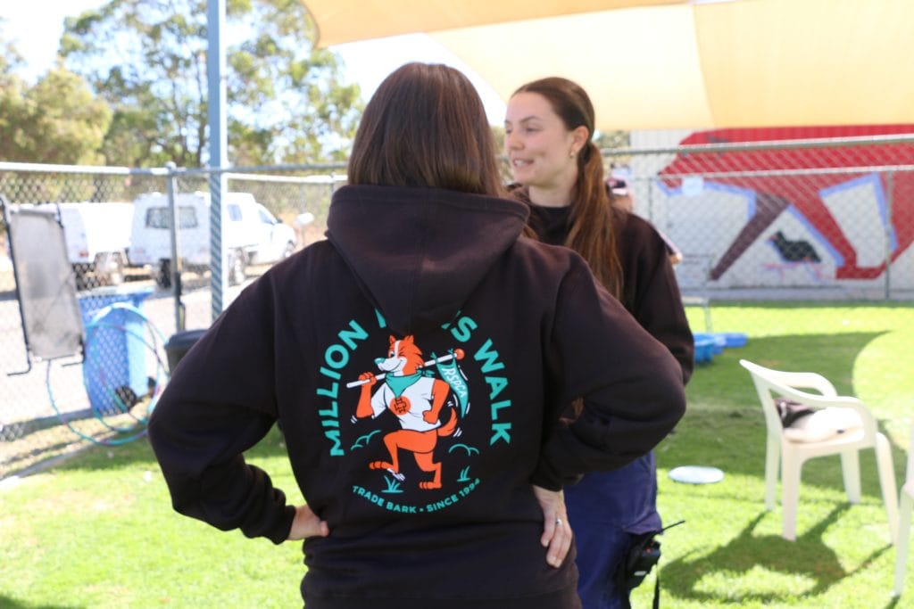 Woman wearing an RSPCA WA Million Paws Walk hoodie in a grassy animal play area